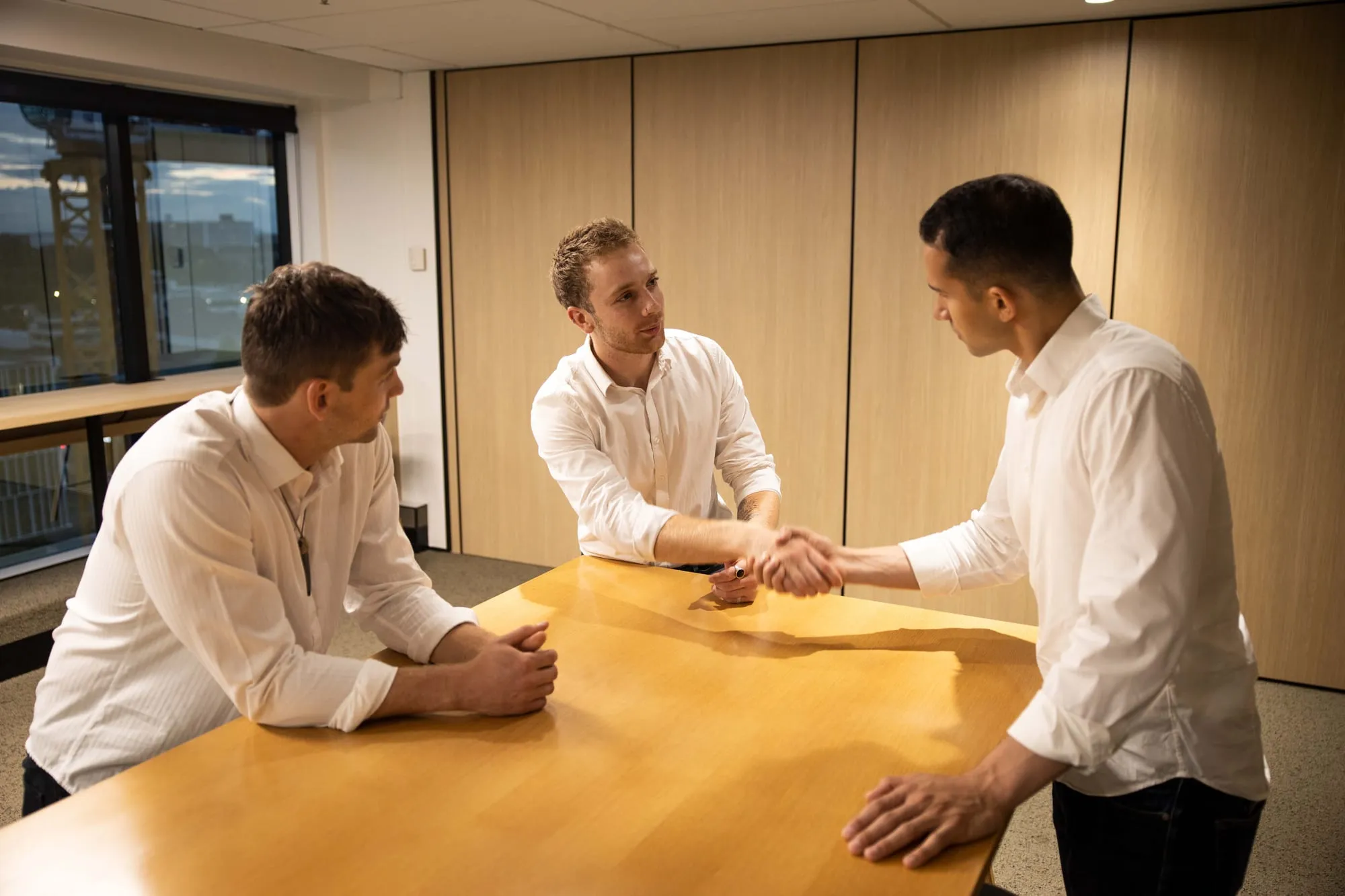 Two Flourish coaches shaking hands with a client across a table