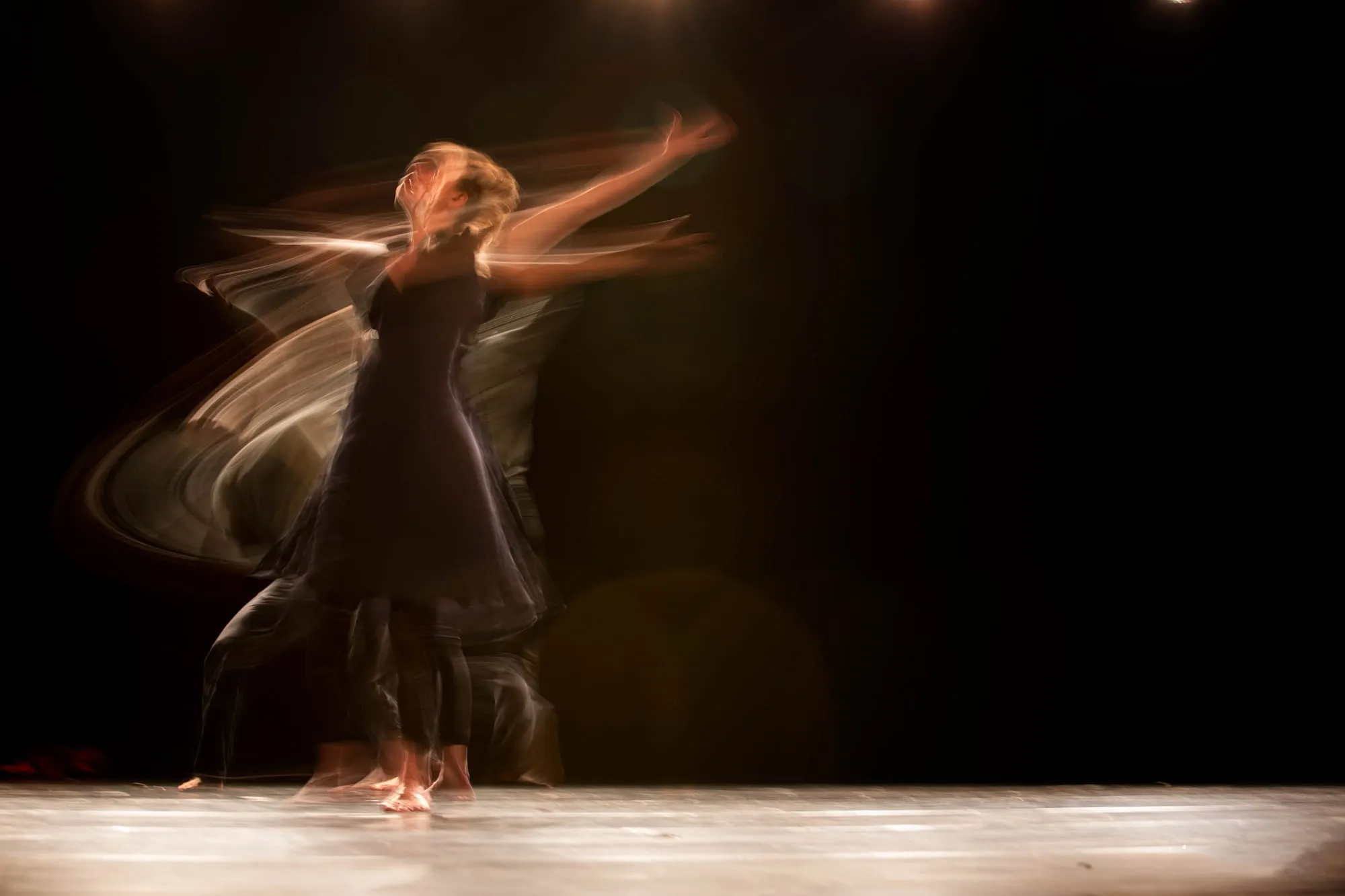 A dancer captured mid-movement, arms sweeping through a full range of motion